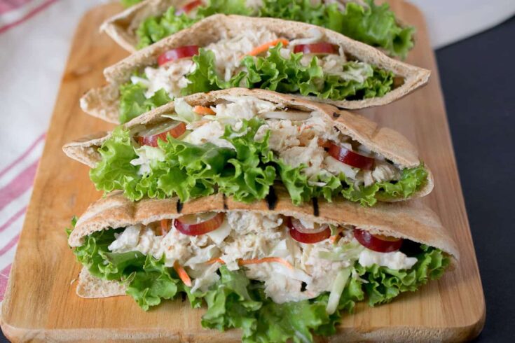 A closeup of tuna salad with coleslaw, grapes and lettuce in pita bread.