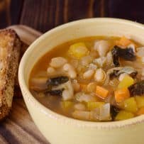 A closeup showing the beans carrot butternut squash and carrots in Tuscan kale soup