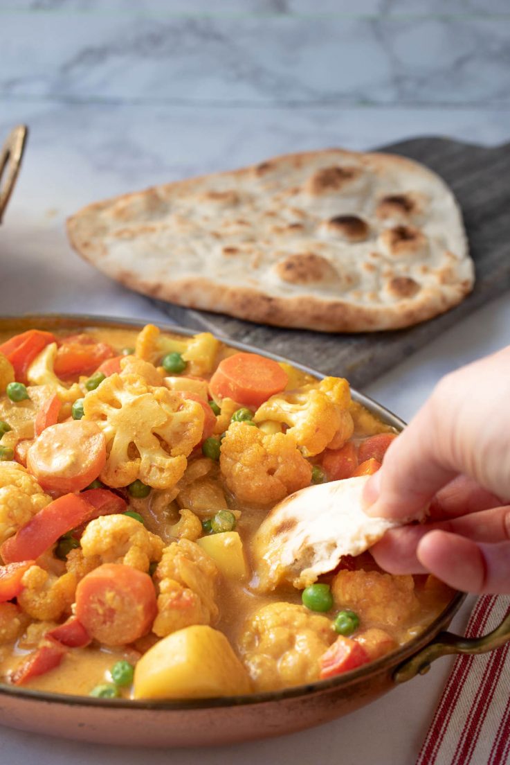 Dipping a piece of naan bread into the curry