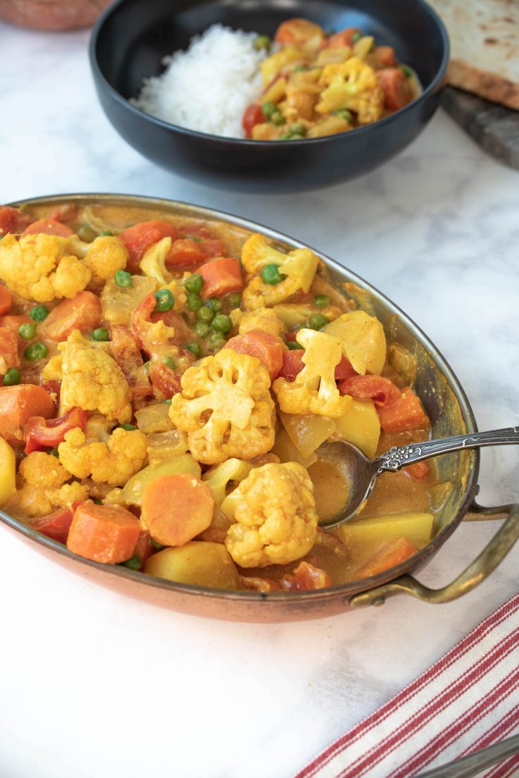 Vegetable Indian Curry in an oval serving bowl with a spoon