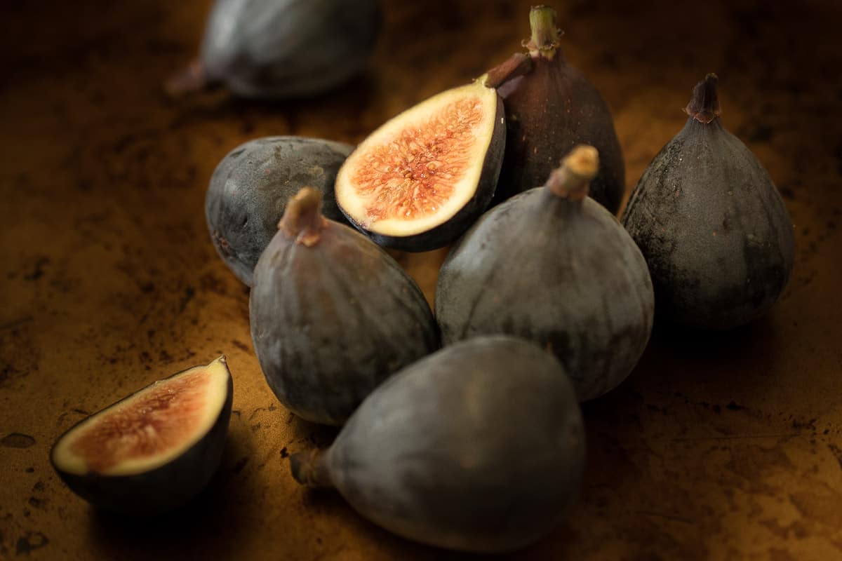 A selection of fresh figs with 1 sliced in half showing the delicious center
