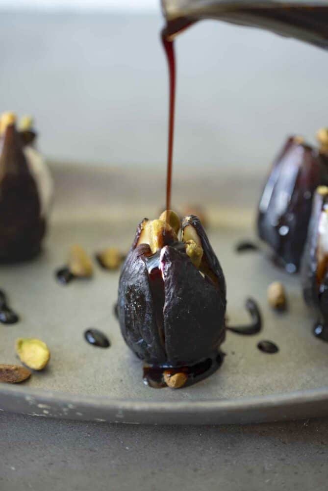 Pouring balsamic glaze over a fresh fig
