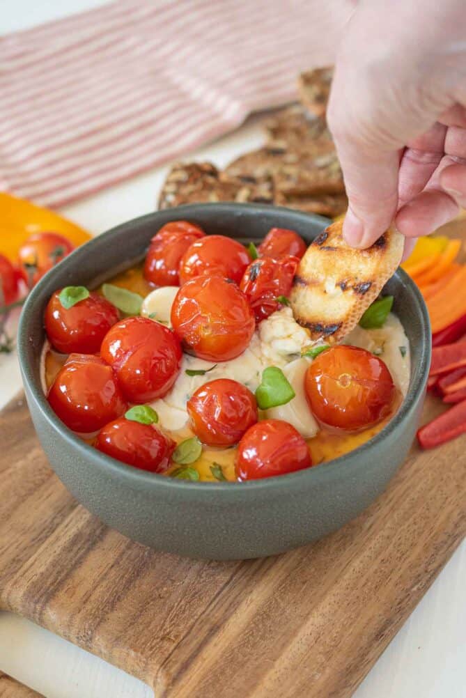 Dipping a piece of grilled bread in whipped cheese