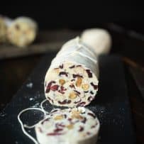 A sliced white chocolate salami showing the nuts and dried cranberries inside.