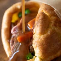 Brown gravy drizzled on Yorkshire pudding and roast beef on a board