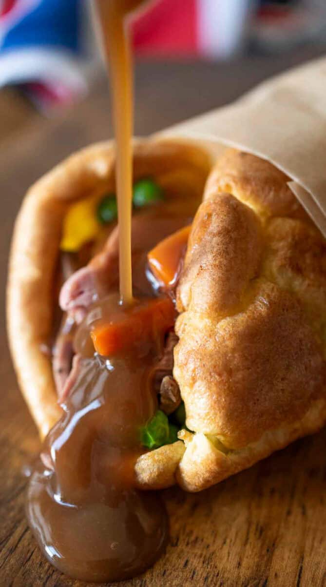 Brown gravy drizzled on Yorkshire pudding and roast beef on a board