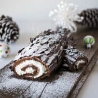 The side view of a chocolate yule log showing the cream filling and dusting of powdered sugar falling like snow