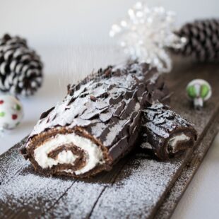 The side view of a chocolate yule log showing the cream filling and dusting of powdered sugar falling like snow