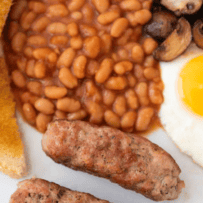 A closeup of homemade pork sausages on a white plate with beans