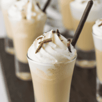 Creamy coffee milkshake in a small glass garnished with whipped cream and chocolate