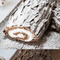 A cake roll coated in chocolate shards and powdered sugar